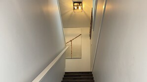 Een houten trap met een leuning, leidend naar een plateau met een lamp en een ingelijst beeld.