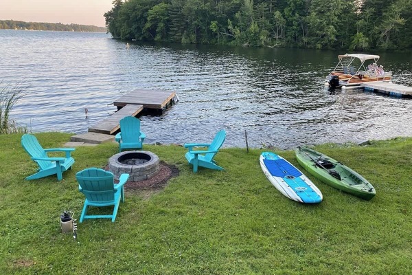 Relax by the water at Little Landing Cottage with Adirondack chairs around the fire pit, perfect for cozy evenings. Enjoy the convenience of a private dock for boating, along with kayaks and paddleboards for fun on Cobbosseecontee Lake.