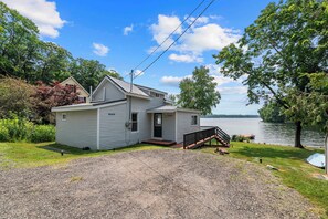 A single-story house with a front porch, a small deck, and a view of a lake.