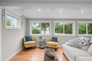 A living room with a sofa, two armchairs, a coffee table, and a view of a lake through large windows.
