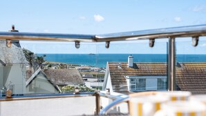 A view from a balcony overlooking a coastal town with houses and the sea.