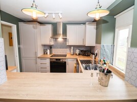 A modern kitchen with white cabinets, a wooden countertop, and a window.