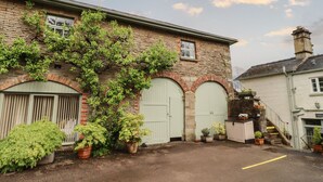 Un bâtiment en pierre avec deux portes vertes, une arche en briques et un escalier menant à un bâtiment blanc.