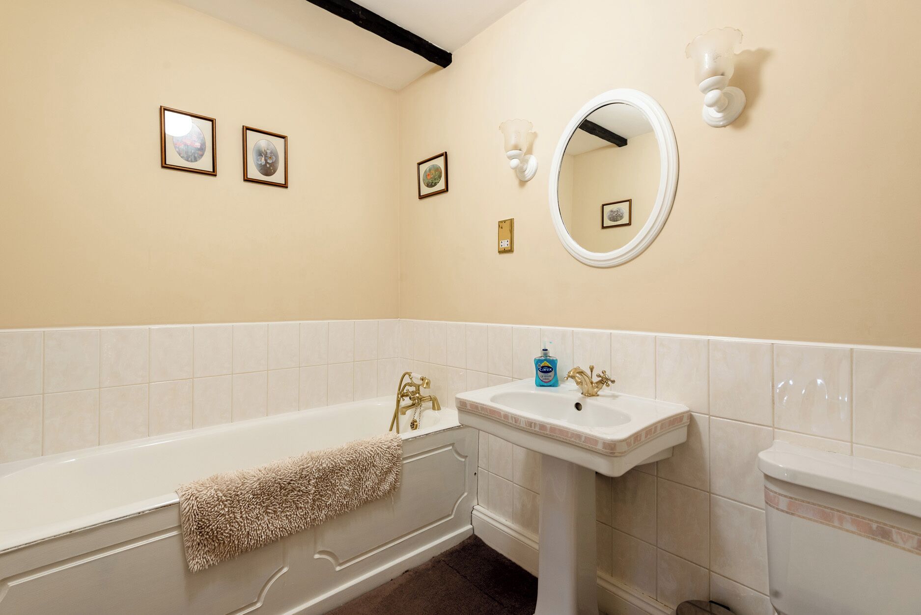 Ein Badezimmer mit einer Badewanne, einem Waschbecken, einem Spiegel und Wandleuchten.