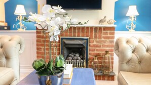 A living room with a blue sofa, a fireplace, and a TV mounted on the wall. - 1 Foresters Rest (Alton)
