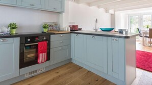 Eine moderne Küche mit hellblauen Schränken, einem schwarzen Backofen und einem roten Handtuch, das an der Backofentür hängt.