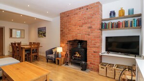 Una sala de estar acogedora con chimenea de ladrillo, muebles de madera, un televisor y una estantería.