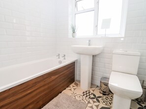 Un baño con una bañera blanca, un lavabo y un inodoro.