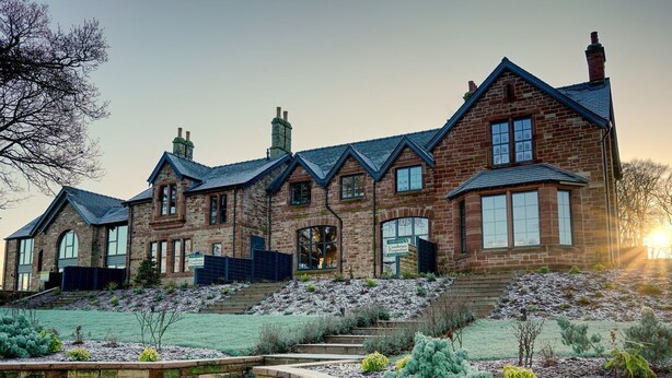 A large brick house with multiple chimneys, a stone staircase, and a well-maintained garden. - Tarn End Cottages 12 (Brampton)
