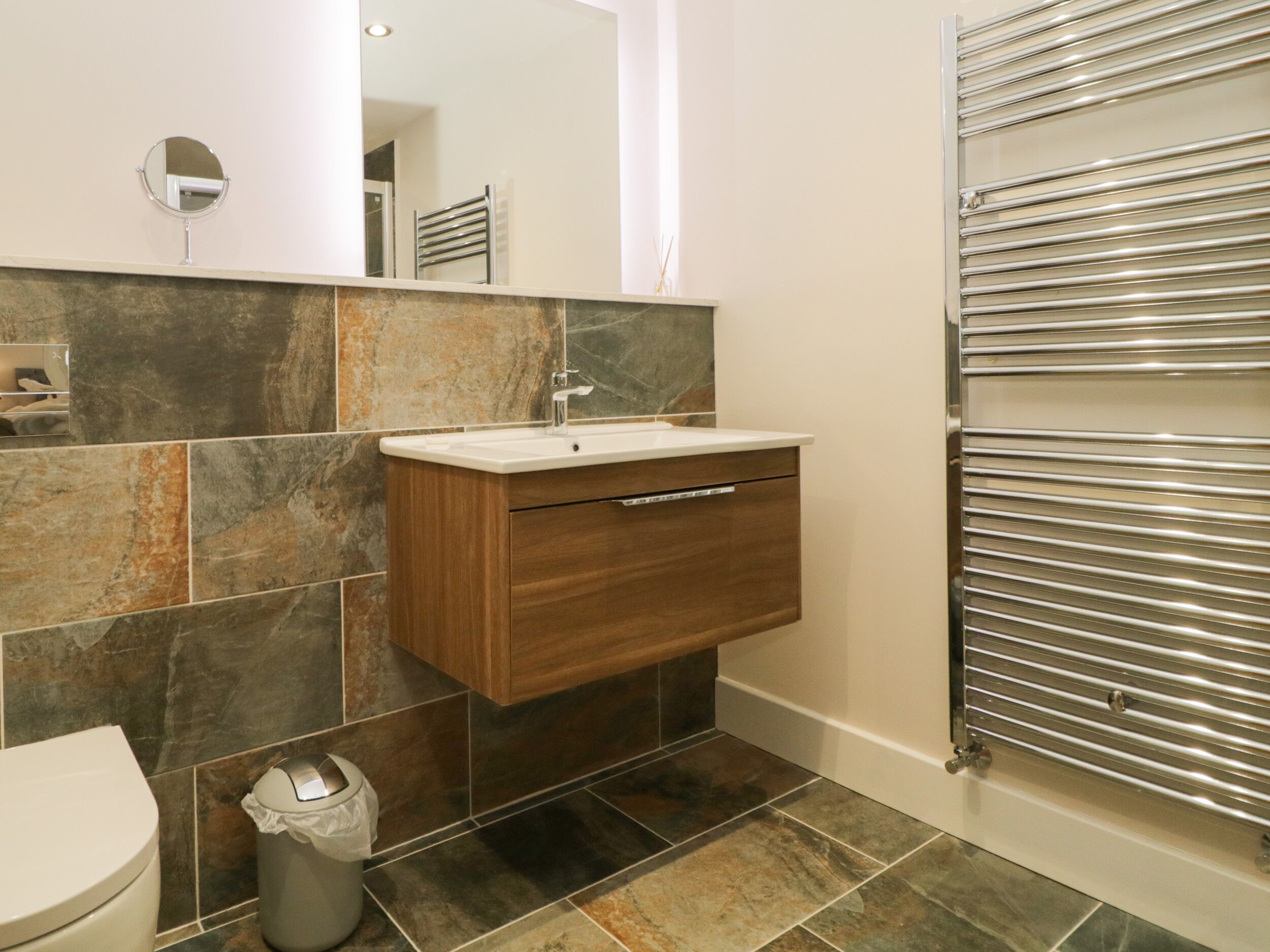 Une salle de bain avec un meuble-lavabo en bois, un miroir, un lavabo et des toilettes.