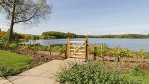 A wooden gate leading to a lake with a clear sky. - Tarn End Cottages 12 (Brampton)