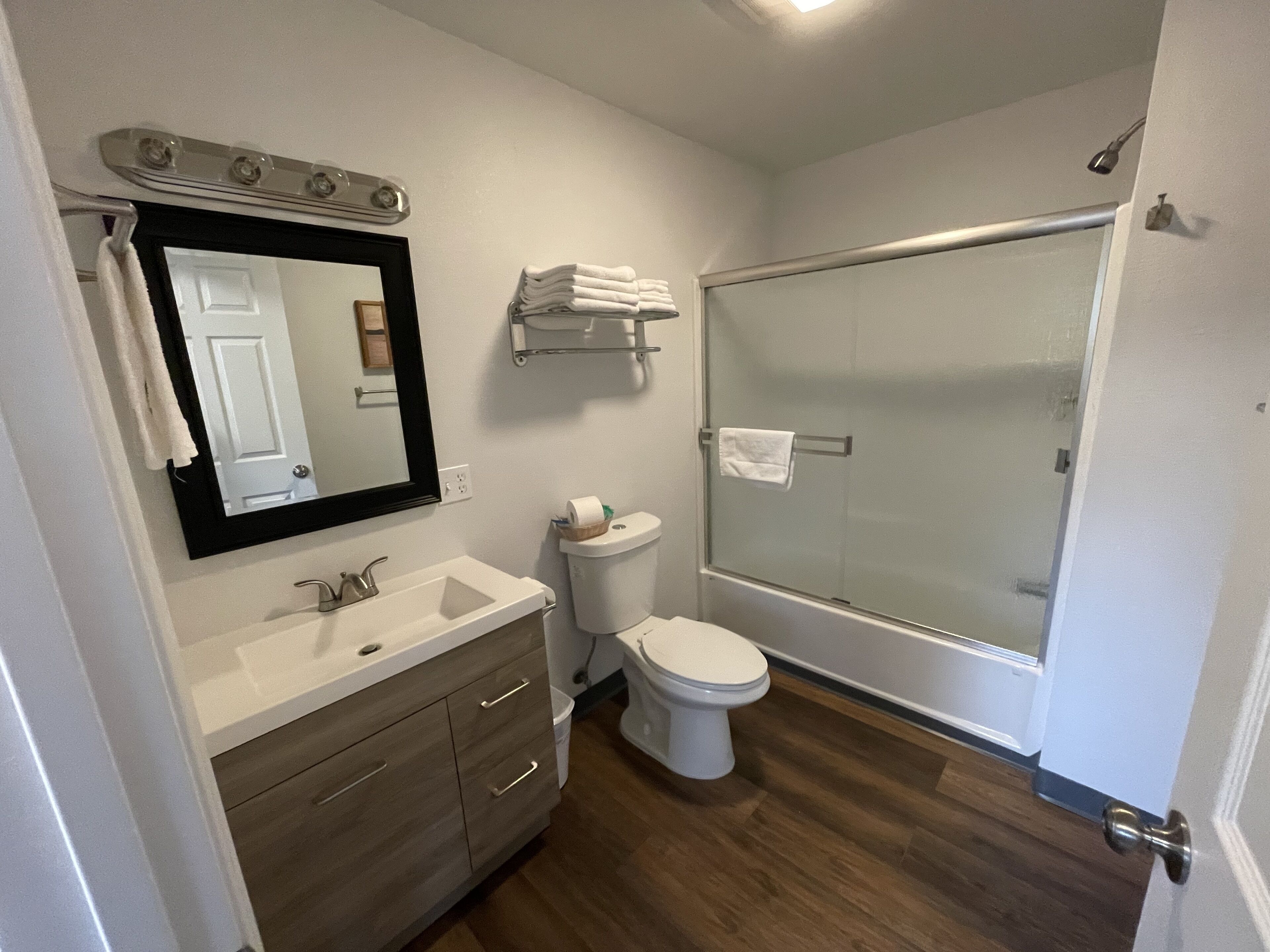 Un baño con lavabo, inodoro y ducha con mampara de vidrio.