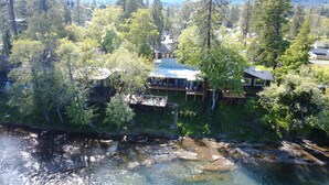Una casa grande con varias terrazas, rodeada de un bosque denso y un río.