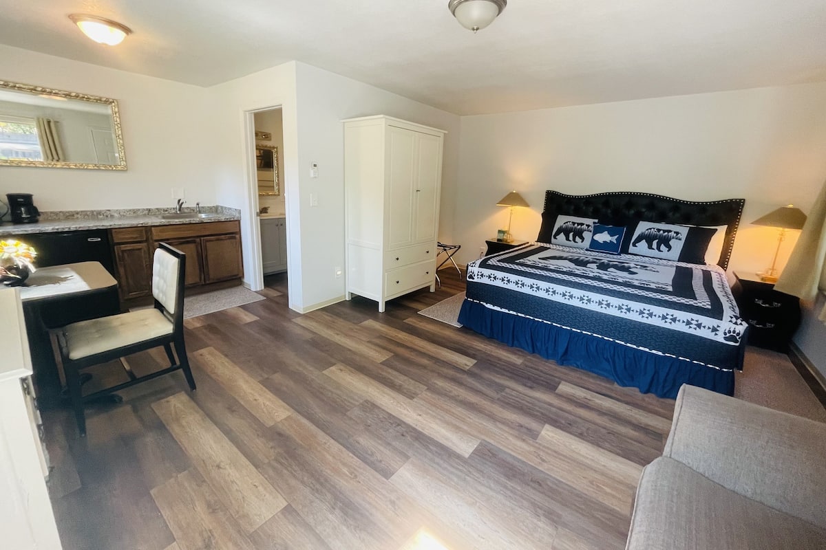 A compact room with a bed, bedside lamps, a desk, and a chair.