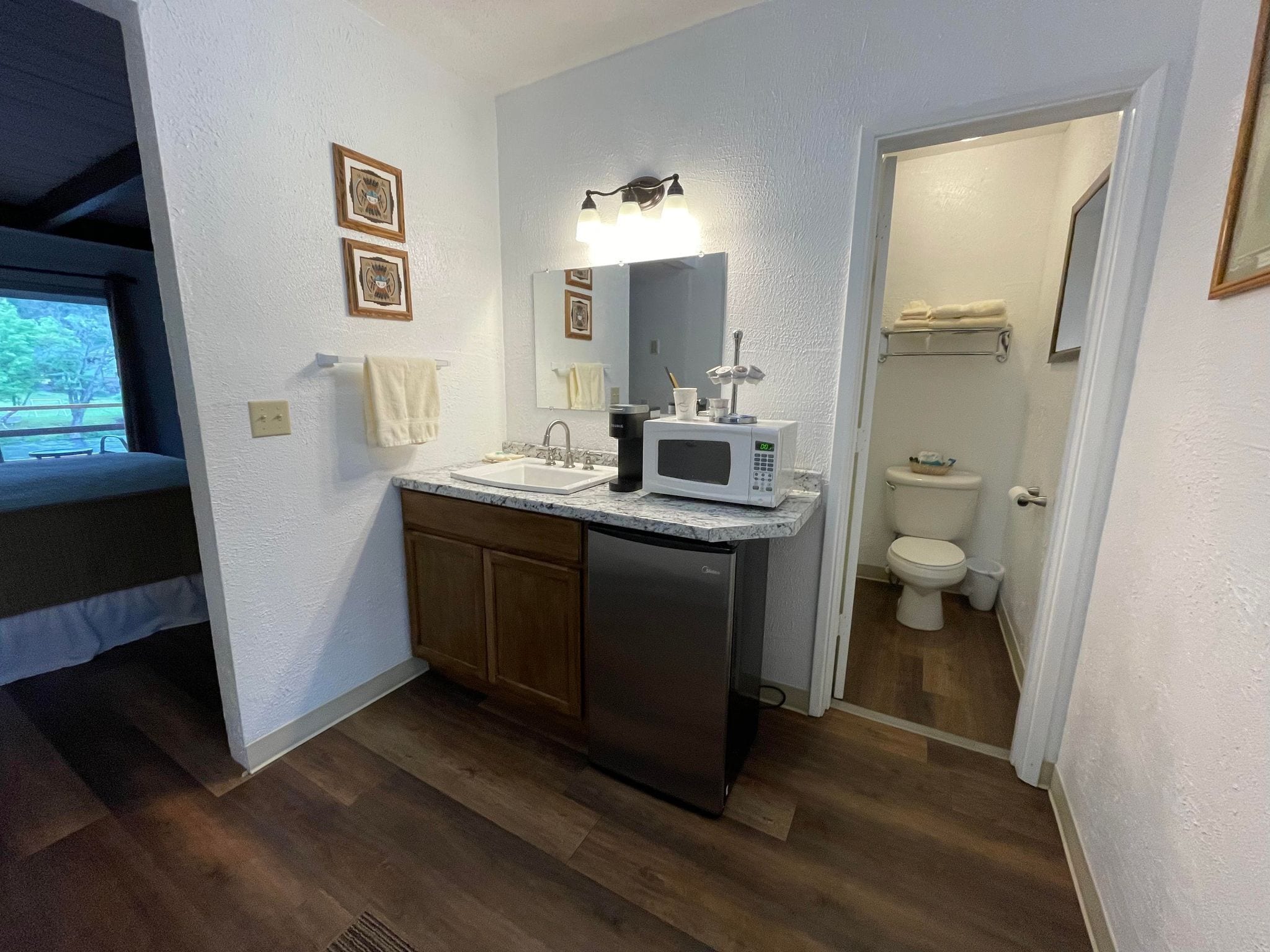 A compact bathroom with a sink, toilet, and a microwave on the countertop.