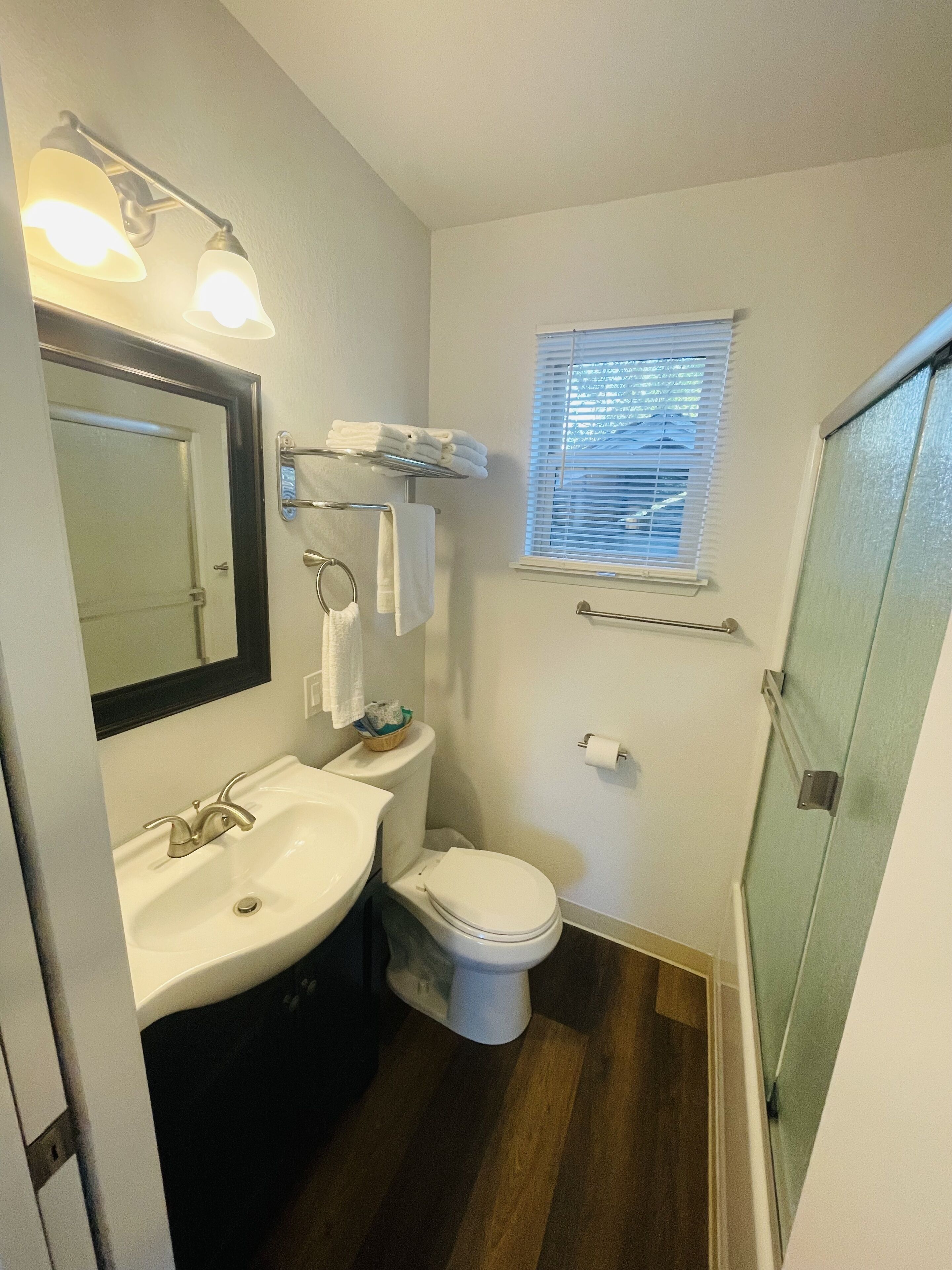 A compact bathroom with a sink, toilet, and a small window.