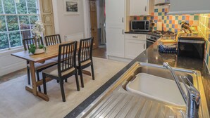 Una cocina con una mesa de madera, sillas, un microondas y un fregadero.