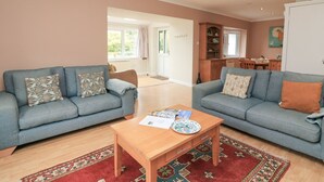 Ein geräumiges Wohnzimmer mit zwei grauen Sofas, einem Holztisch und einem roten Teppich mit Muster.