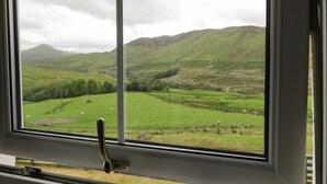 A window view of a green landscape with hills and a mountain in the distance. - Brae Mhor Cottage (Fort William)