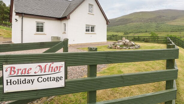 A white cottage with a sign reading "Brae Mhor Holiday Cottage" in front. - Brae Mhor Cottage (Fort William)