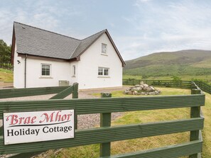 Ett vitt hus med en skylt framför som visar texten ”Brae Mhor Holiday Cottage”.