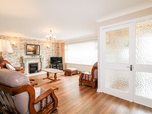 A living room with a fireplace, a television, and a large window with curtains. - 27 Pinewood Hill (Newry)