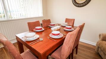 A dining room with a wooden table set for six, surrounded by six chairs.