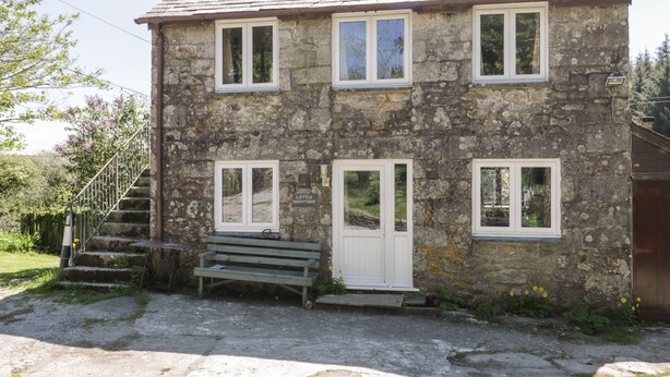 A stone building with a wooden bench, a staircase, and a door. - Little Trespettigue (Launceston)