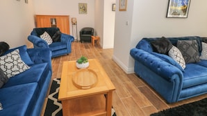 Una sala de estar moderna con dos sofás azules, una mesa de centro de madera y un tapete negro.