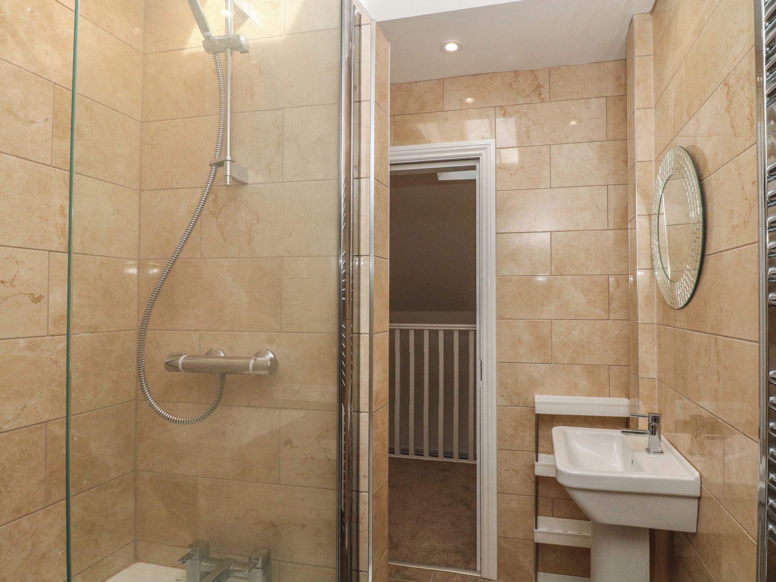 A bathroom with a glass-enclosed shower, a white sink, and a mirror on the wall.