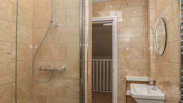 A bathroom with a glass-enclosed shower, a white sink, and a mirror on the wall.