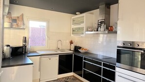 Una cuina moderna amb armaris blancs, un taulell negre i terres de rajoles amb disseny.