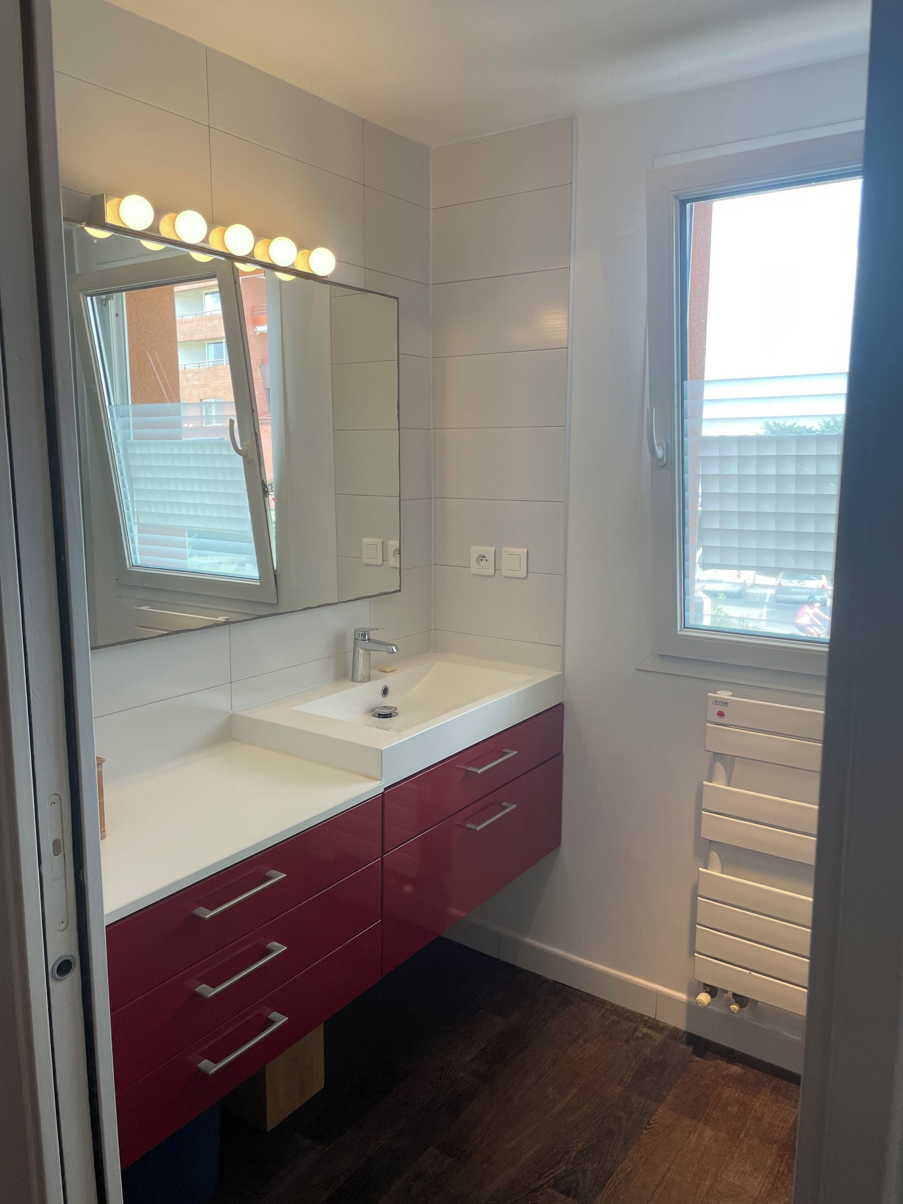 A bathroom with a vanity, mirror, and lights.