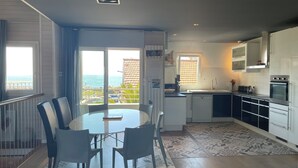 Una cuina moderna amb vistes al mar, una zona de menjador amb cadires i una petita illa.