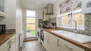 A modern kitchen with a wooden countertop, stainless steel appliances, and a large window.