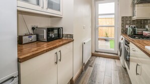 A compact kitchen with white cabinets, a microwave, a toaster, and a gas stove.