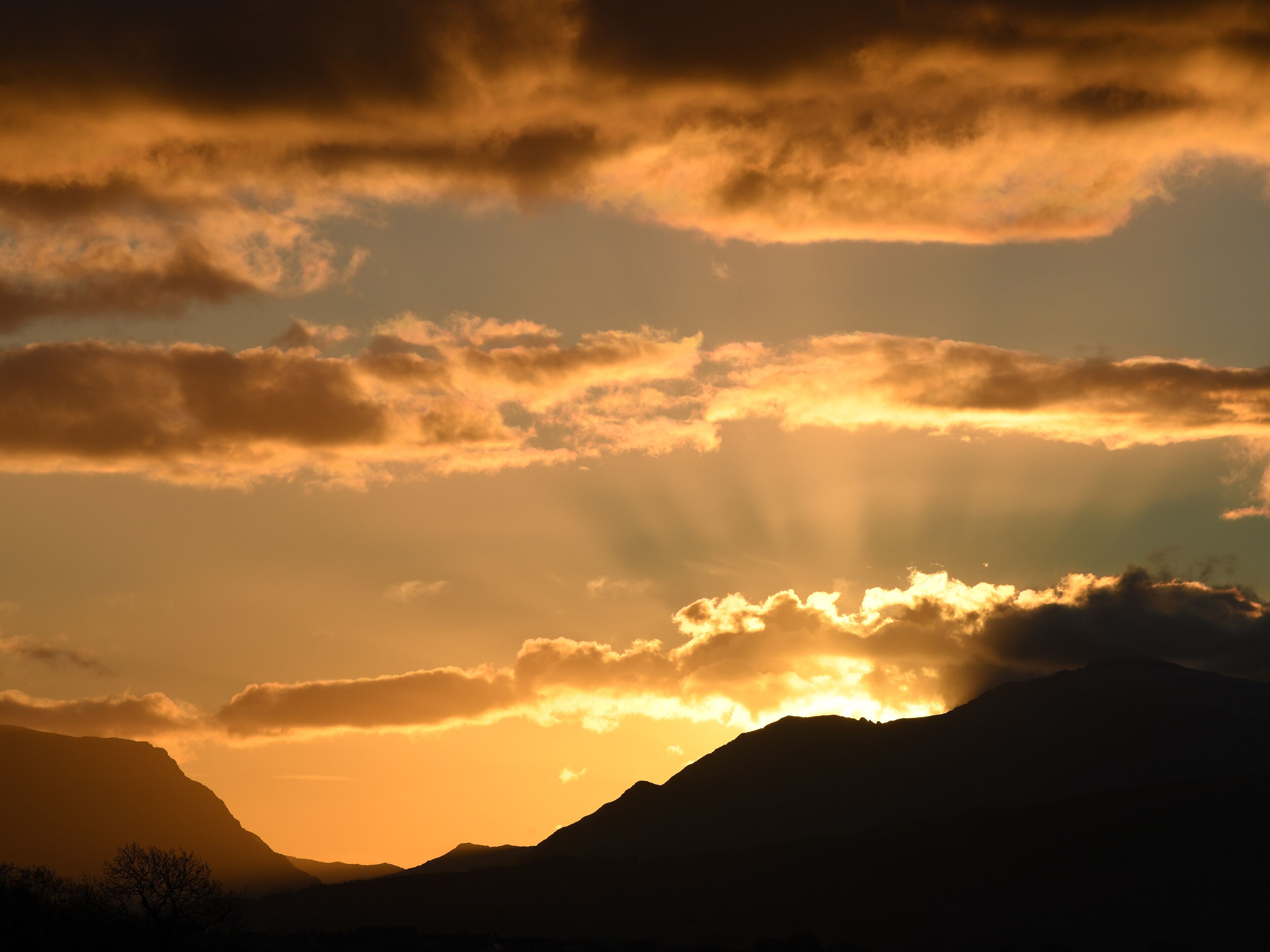 A mountain silhouette with a sunset and clouds.