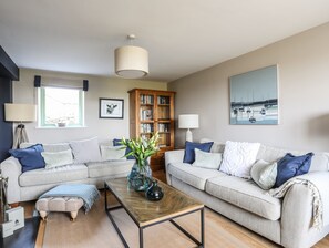 Un salon avec deux canapés, une table basse, une bibliothèque et un tableau accroché au mur.