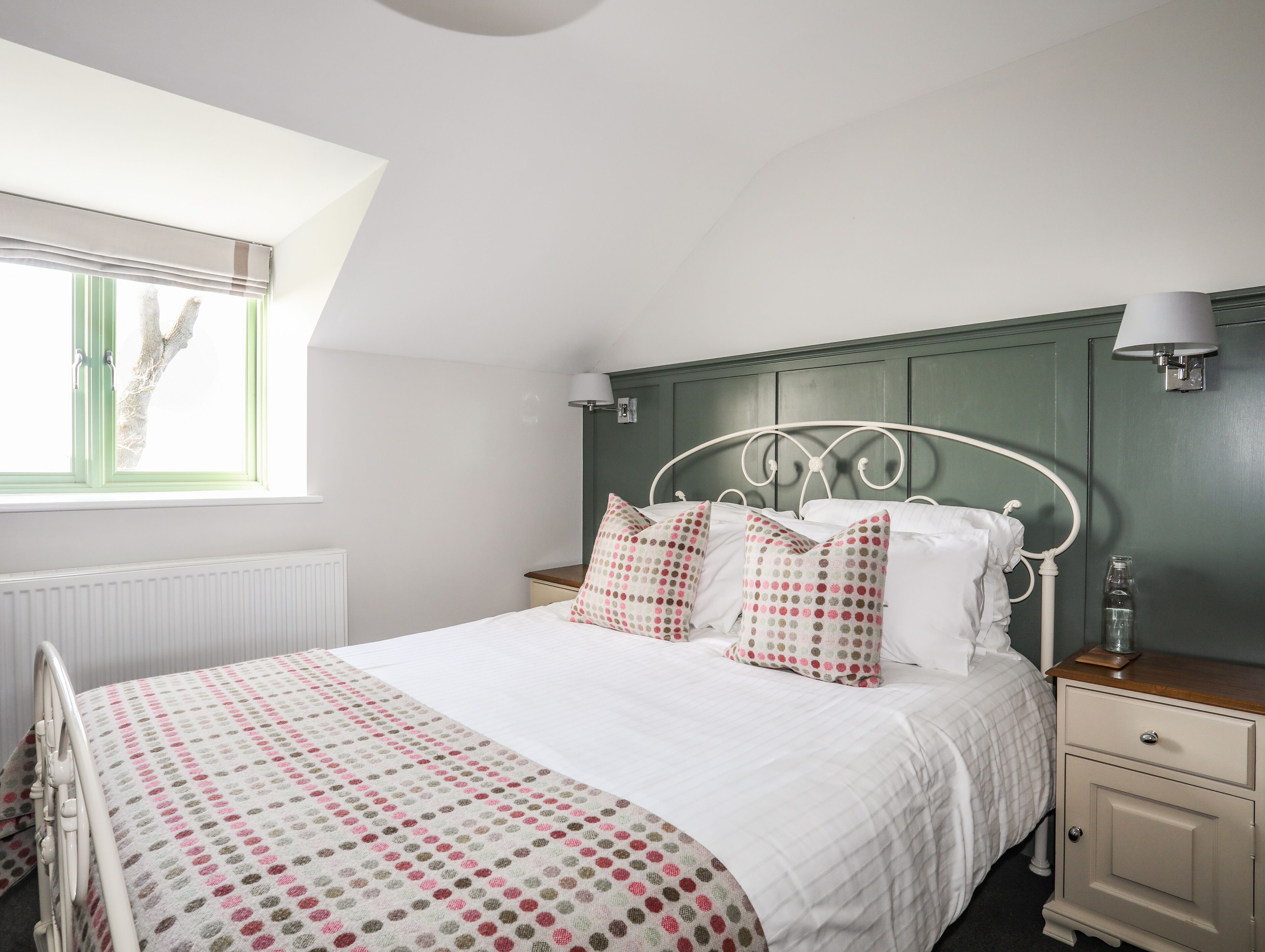 A neatly arranged bedroom with a bed, bedside tables, a window, and a radiator.