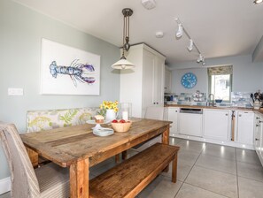 Un espace repas comprenant une table en bois, un banc et un luminaire fixé au mur.