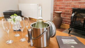 A room with a wooden table, a metal champagne bucket, several wine glasses, a vase with flowers, a book, a radiator, a brick wall, and a fireplace. - The Old Church (York)