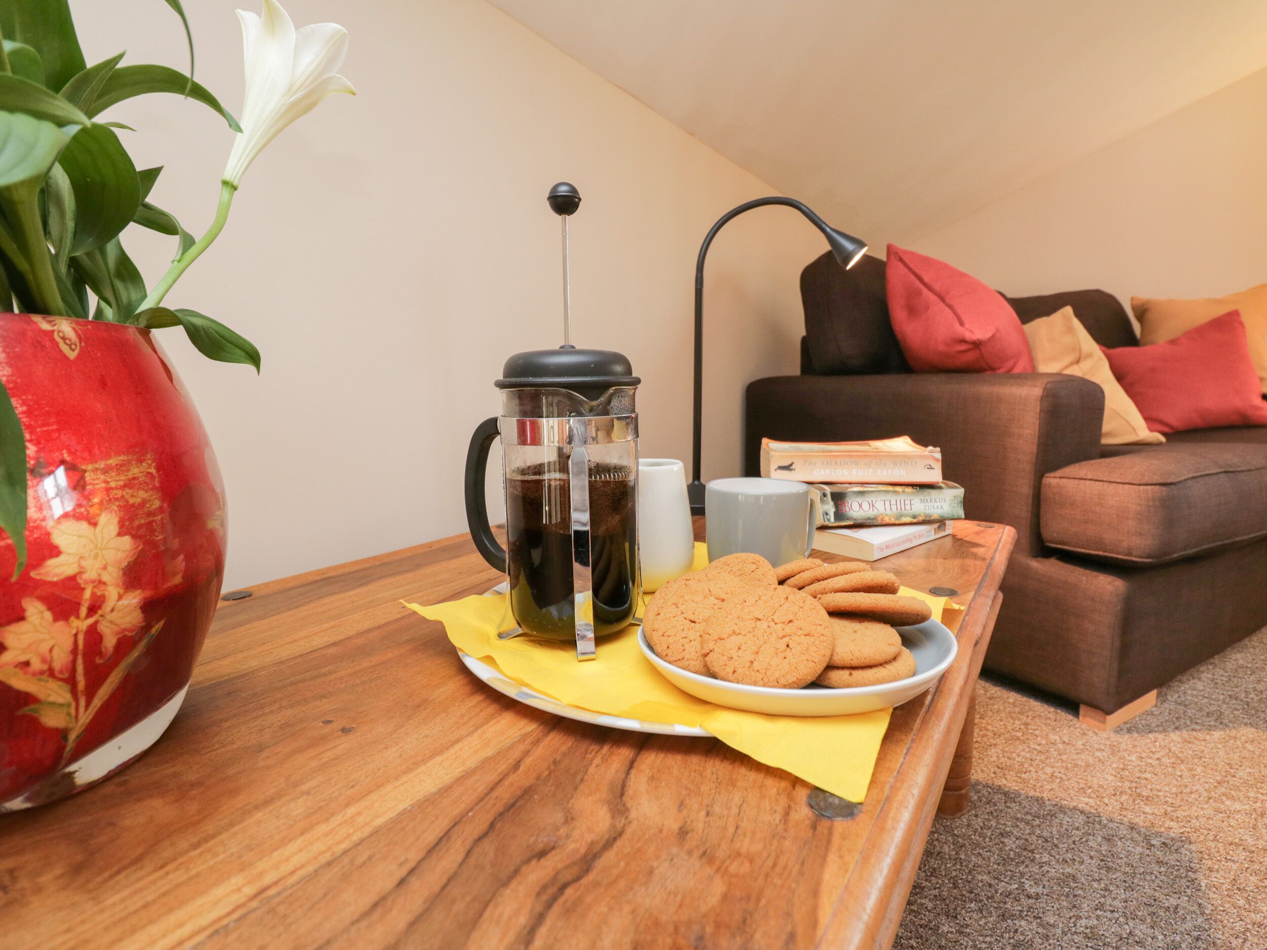 Un salon confortable avec une machine à café, des biscuits et un livre posés sur une table en bois.
