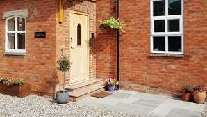 A brick building with a wooden door, a sign reading "The Old Church," and potted plants. - The Old Church (York)