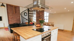 A modern kitchen with a wooden countertop, a built-in oven, and a glass stove top. - The Old Church (York)