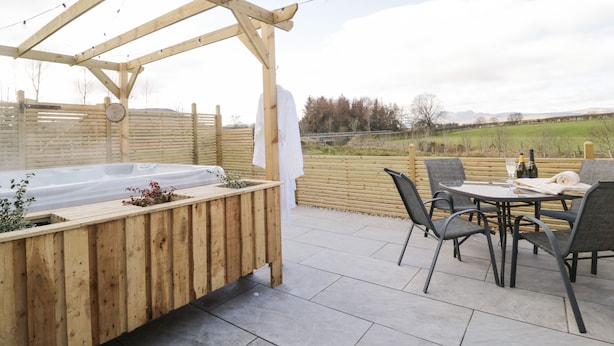 Ein Außenbereich mit Whirlpool, einer Pergola, Sitzgelegenheiten und Blick auf die Landschaft.