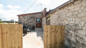 A stone building with a wooden door and steps leading to a covered entrance. - The Old Cow Shed (Banwell)