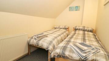 A small, cozy bedroom with two single beds, a radiator, and a 'DREAM' sign on the wall.