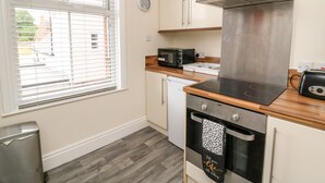 A modern kitchen with a stainless steel range hood, a microwave, and a built-in oven. - The Pebbles (Hornsea)