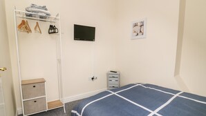 A bedroom with a bed, a wardrobe, a television, and a small desk. - The Pebbles (Hornsea)