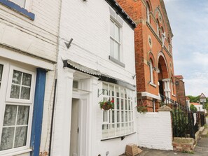 A row of white brick houses with a red brick building in the background. - The Pebbles (Hornsea)